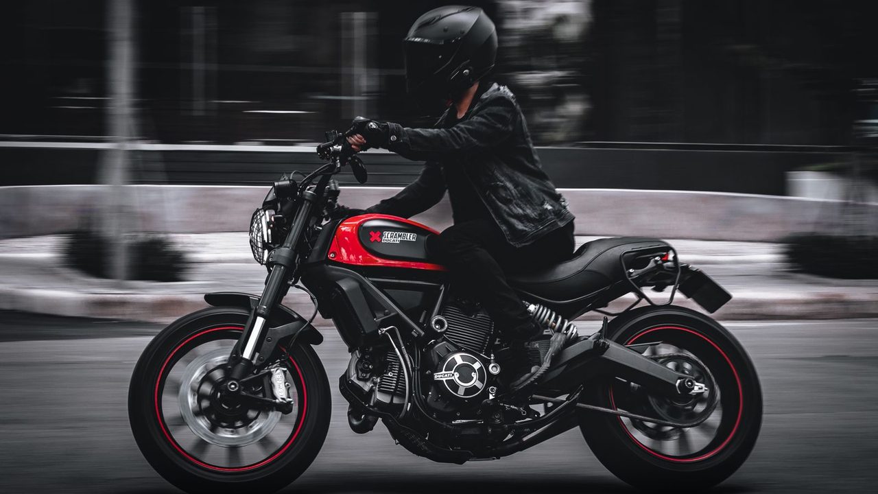 Motorista con chaqueta textil de moto junto a su moto