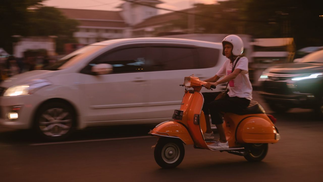Casco jet con pantalla larga sobre el asiento de un scooter