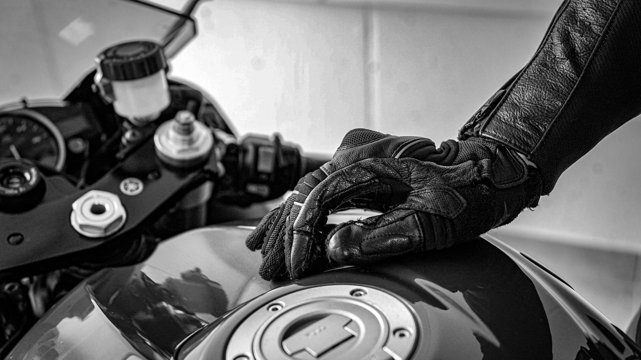 Persona limpiando y engrasando la cadena de una moto